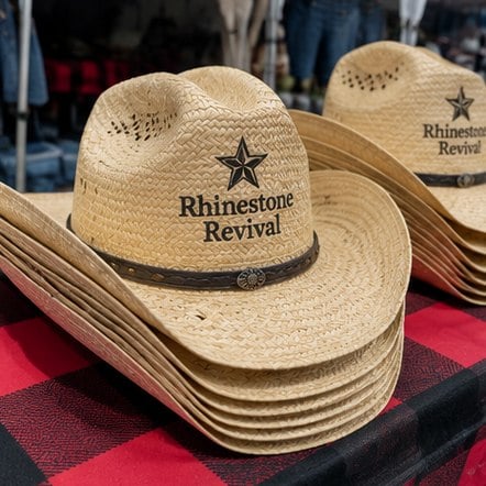 Custom straw cowboy hats at a festival merch stand